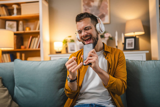 Um homem adulto segurar smartphone celular em casa feliz sorriso cantar - Foto, Imagem