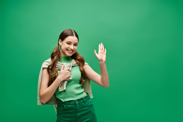 Nuori nainen hänen 20s dons silmiinpistävä vihreä paita ja matching housut studiossa ympäristössä, tihkuu ajatonta eleganssia ja tyyliä. - Valokuva, kuva
