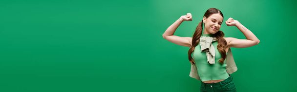 Молодая женщина в возрасте 20 лет позирует на ярком зеленом фоне в студии. - Фото, изображение