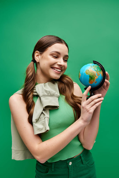 Una giovane donna sulla ventina tiene in mano un piccolo globo, raffigurante la cura e la preoccupazione per il mondo. - Foto, immagini