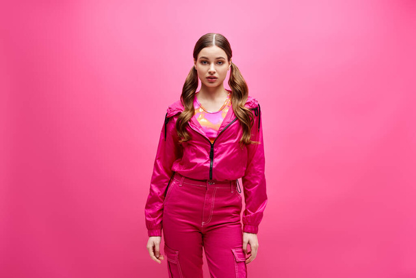 A young, stylish woman in her 20s wearing a pink outfit poses elegantly in front of a matching pink background. - Photo, Image