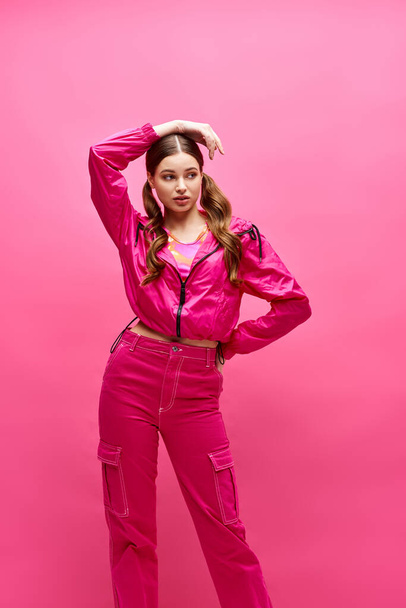 Μια νεαρή γυναίκα γύρω στα 20, στιλάτη με ροζ, ποζάρει για ένα πορτραίτο σε φόντο στούντιο. - Φωτογραφία, εικόνα