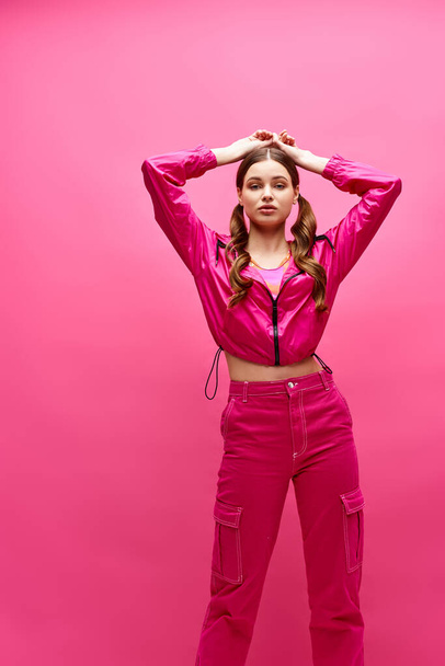 A woman in a pink outfit strikes a pose in a stylish studio setting with a pink background. - Photo, Image