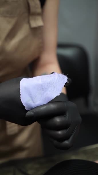 Mistr v černých lékařských rukavicích nanáší na klientovo podpaží vosk. Depilace voskem. Voskování - odstranění vlasů - Záběry, video