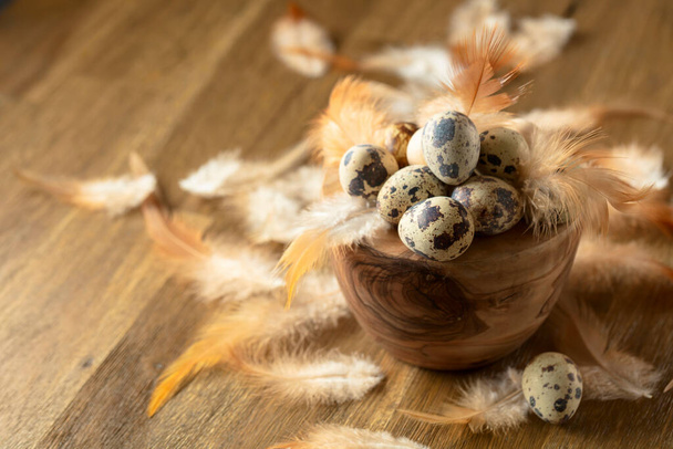 Quail eggs and feathers on a old wooden table. - Photo, Image