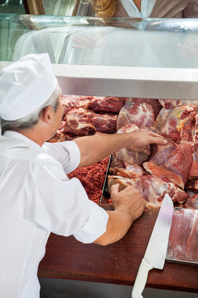 Butcher Arranging Fresh Meat In Display Counter - Photo, Image