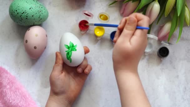 niño colorear el huevo de Pascua, mesa de madera con tulipanes - Metraje, vídeo