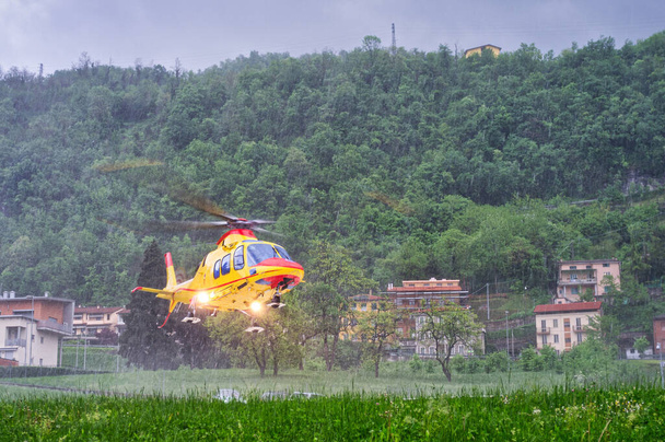 Ιατρική υπηρεσία έκτακτης ανάγκης ελικοπτέρου απογειώνεται από ελικοδρόμιο νοσοκομείου σε δυνατή βροχή κατά τη διάρκεια σοβαρής καταιγίδας - Φωτογραφία, εικόνα