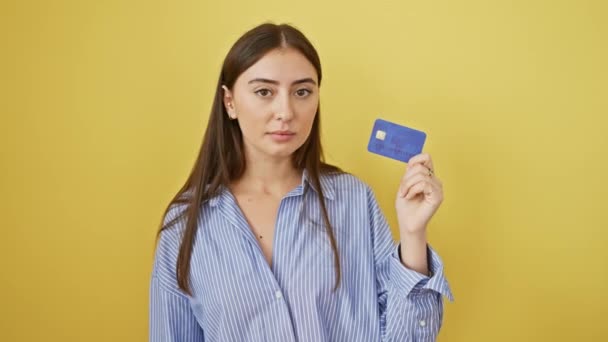 Jonge, zelfverzekerde Spaanse vrouw die financiele bewegingen beraamt, kredietkaart in de hand. mooie, zelfverzekerde uitdrukking - Video