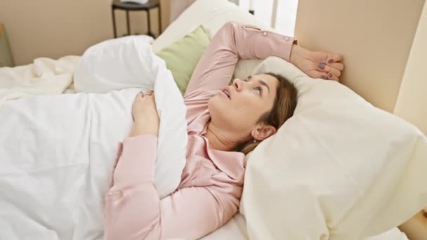 Una giovane donna riposa in una camera da letto luminosa, trasudando un senso di pace e relax. - Filmati, video
