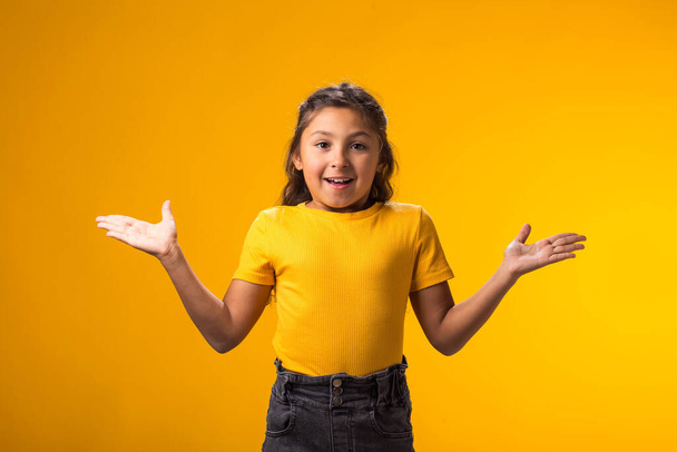 Retrato de menina garoto animado de mãos erguidas sobre fundo amarelo. Conceito de emoção - Foto, Imagem