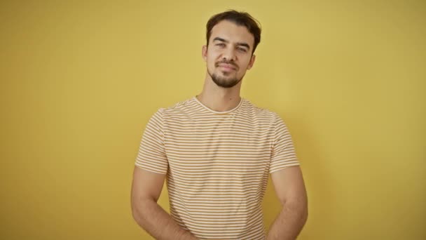 Un jeune homme hispanique souriant en t-shirt rayé, une image de bonheur et de confiance avec les bras croisés sur fond jaune - Séquence, vidéo