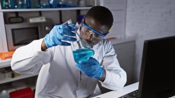 Ein fokussierter afrikanischer Wissenschaftler analysiert eine blaue chemische Lösung in einem modernen Laborumfeld - Filmmaterial, Video