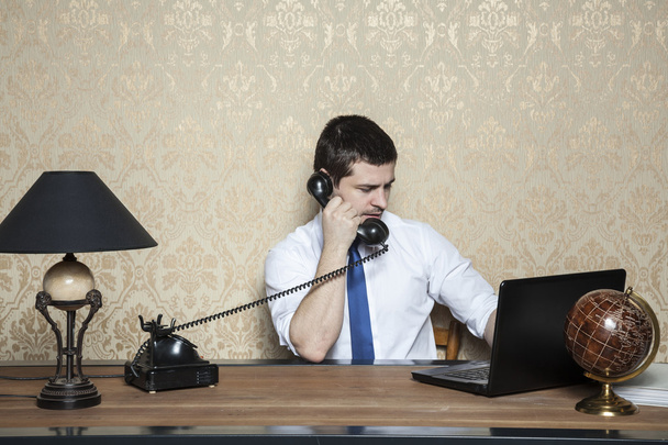 бизнесмен работает на ноутбуке и разговаривает по телефону
 - Фото, изображение
