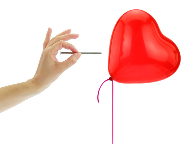 Nail about to pop a heart balloon isolated on white - Photo, Image