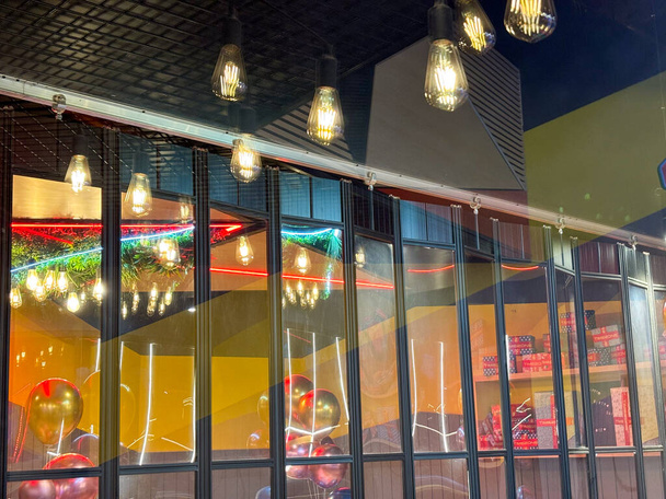 Un interior de restaurante lleno de multitud de luces colgando del techo, iluminando el espacio y creando un ambiente vibrante para los comensales. Las luces proyectan un cálido resplandor sobre las mesas y el suelo, añadiendo un toque de elegancia al comedor exp - Foto, Imagen