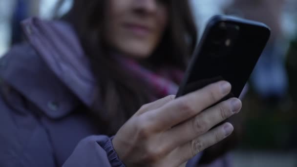Nő kezében telefon, közelről kéz, miközben rack összpontosít, hogy szembenézzen a mosollyal, 30-as női személy elkötelezett a modern technológia - Felvétel, videó