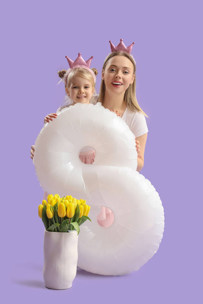 Little girl with her mother, tulips and balloon in shape of figure 8 on lilac background. International Women's Day - Photo, Image