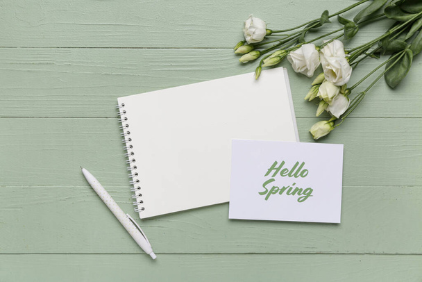 Üdvözlőlap szöveggel HELLO SPRING, notebook és gyönyörű fehér eustoma virágok zöld fa háttér - Fotó, kép