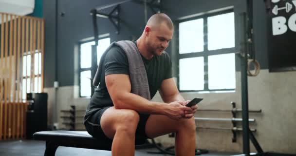 Athlete, man and phone in gym for relax with happiness, break and chat before exercise, workout or training. Bodybuilder, person and smartphone for internet, text message and fitness progress on app. - Footage, Video
