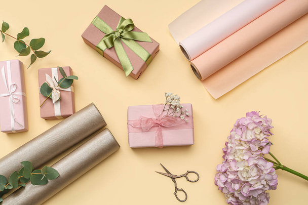 Cajas de regalo con papel de regalo, hermosas hortensias y flores de gypsophila sobre fondo amarillo. Día Internacional de la Mujer - Foto, Imagen