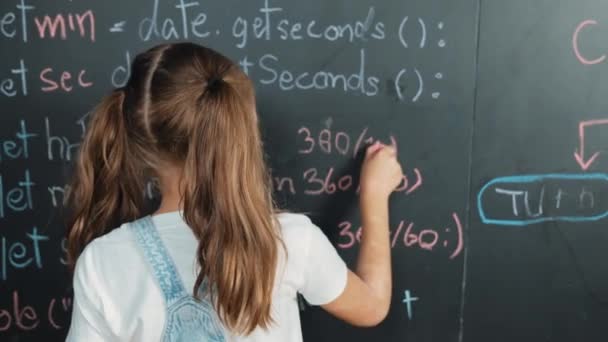 Happy caucasian girl writing blackboard and turnaround to waving at camera while standing at board with engineering prompt or coding, programing system written in STEM technology classroom. Erudition. - Footage, Video