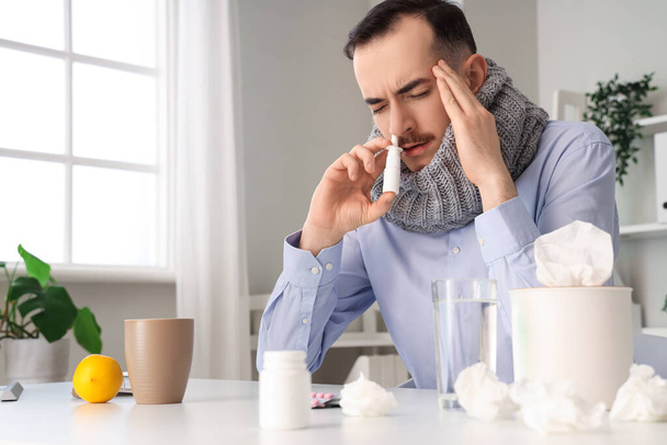 Homme d'affaires malade avec écharpe en utilisant des gouttes nasales au bureau - Photo, image