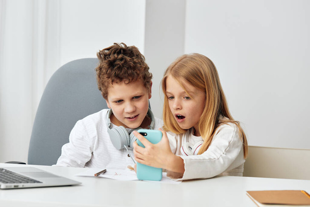 Teini-ikäinen poika ja tyttö opiskelevat yhdessä kannettavilla tietokoneilla kotona He ovat onnellisia ja harjoittavat online-koulutusta, käyttävät kuulokkeita ja kirjoittavat tietokoneisiinsa Olohuone toimii heidän työhuoneenaan. - Valokuva, kuva