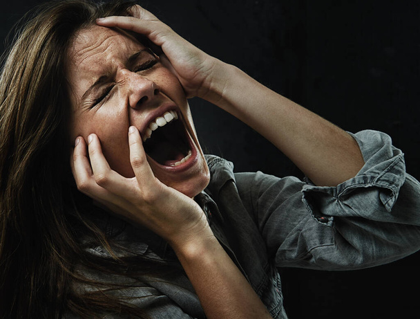 Face, stress and horror with woman yelling in studio on black background for reaction to fear. Phobia, mental health and breakdown with scared young person in dark for drama, nightmare or terror. - Photo, Image