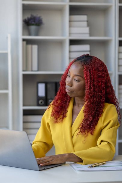 Gyönyörű afrikai üzletasszony ül a cégnél, egy női alkalmazott információt keres, hogy felkészüljön egy találkozóra, aki az asztalánál ül, és különböző dolgokat csinál.. - Fotó, kép