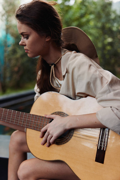 Kobieta gra na gitarze akustycznej przed basenem w białej koszuli - Zdjęcie, obraz