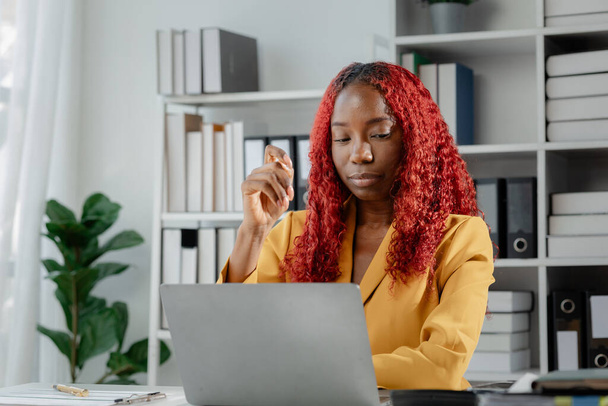 Krásná africká podnikatelka sedí v soukromé kanceláři ve společnosti, Žena zaměstnanec hledá informace pro přípravu na schůzku, sedí u svého stolu dělat různé věci. - Fotografie, Obrázek