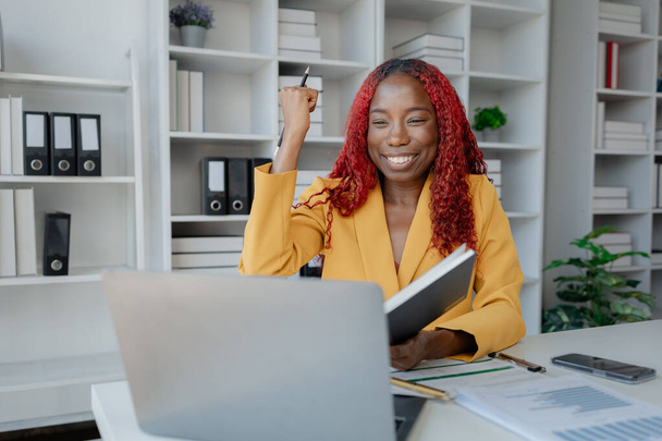 Gyönyörű afrikai üzletasszony boldogan dolgozik a privát irodájában, egy gyönyörű afrikai női alkalmazott boldog az irodájában, mert elvégezte a feladatát.. - Fotó, kép