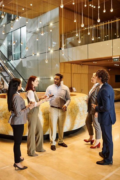 A varied group of business individuals engaging in conversation in a sleek lobby. - Photo, Image