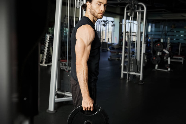Un hombre enfocado en atuendo de gimnasio sosteniendo una barra, mostrando determinación y fuerza durante su rutina de entrenamiento. - Foto, imagen