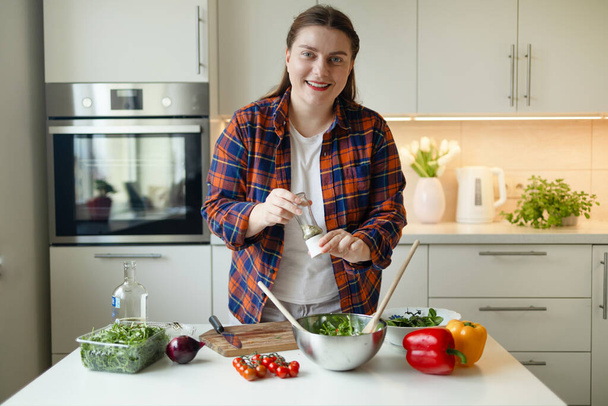 Retrato de una ama de casa está preparando deliciosa ensalada de verduras con tomate, rúcula, pimiento rojo y amarillo en la cocina. Comida saludable. Ensalada vegana. Dieta. Concepto de dieta. Estilo de vida saludable. Cocinar - Foto, Imagen