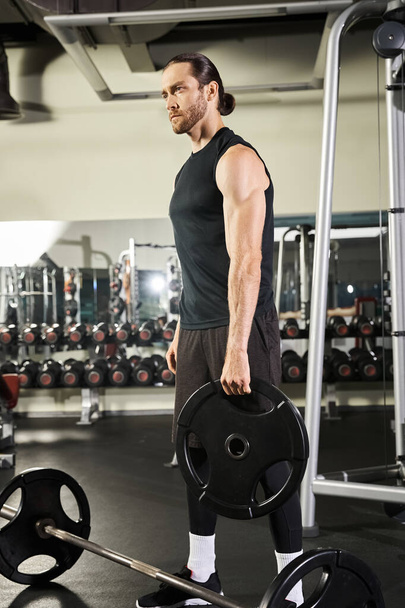 Atletyczny mężczyzna na siłowni trzymający sztangę, pokazujący siłę i determinację podczas treningu. - Zdjęcie, obraz