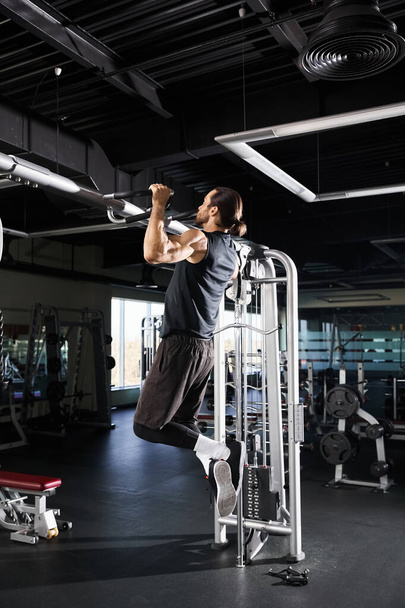 Atletický muž v aktivním oblečení dělá vytáhnout na stroji v tělocvičně. - Fotografie, Obrázek