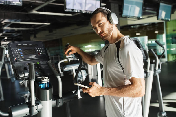 Sportowiec w aktywnym ubraniu biega na bieżni, w pełni zanurzony w treningu ze słuchawkami na uszach. - Zdjęcie, obraz