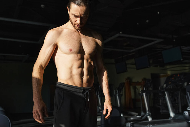 ジム環境で立っているシャツのない筋肉質の男性,積極的に作業や身体トレーニングに従事. - 写真・画像