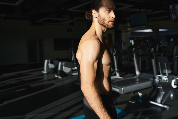 A shirtless, muscular man stands confidently in front of a line of treadmills, ready for a powerful workout session. - Photo, Image