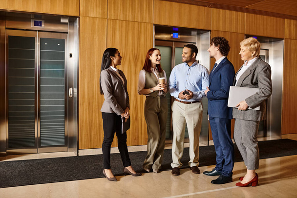 Μια πολυεθνική ομάδα επιχειρηματιών στέκεται μπροστά από ένα ασανσέρ, έτοιμοι να κινηθούν. - Φωτογραφία, εικόνα