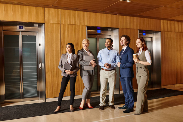 Een gevarieerde groep professionals die samen voor liftdeuren staan. - Foto, afbeelding