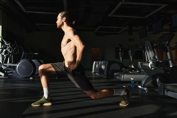Мужчина без рубашки с мускулами делает приседания в спортзале. - Фото, изображение