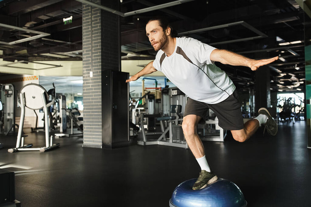 Um homem musculoso executa criativamente exercícios em uma bola de exercício em um ginásio. - Foto, Imagem