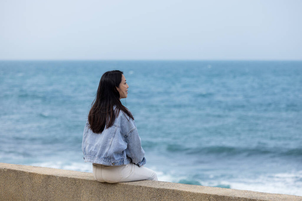 Женщина сидит на берегу моря - Фото, изображение