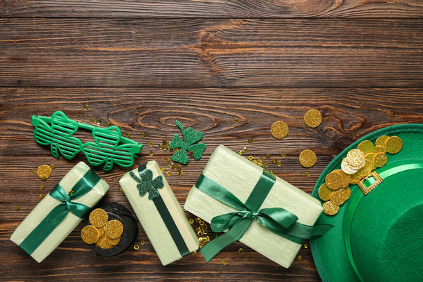 Cadeaudoosjes met kabouter hoed, pot met gouden munten en plastic brillen voor St. Patrick 's Day viering op houten achtergrond - Foto, afbeelding