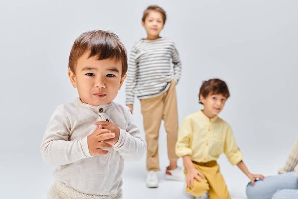 Eine Gruppe kleiner Kinder einer asiatischen Mutter steht zusammen in einem Atelier vor grauem Hintergrund. - Foto, Bild