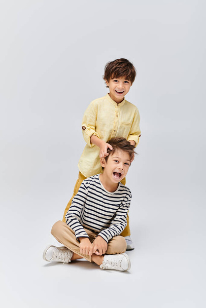Zwei kleine Jungen, die auf dem Boden sitzen, staunen mit weit geöffnetem Mund in einem Atelierraum. - Foto, Bild