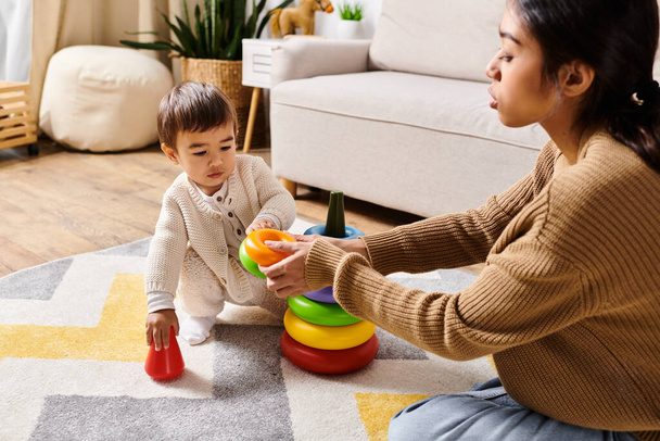 Una giovane madre asiatica e il suo piccolo figlio giocano felicemente sul pavimento del soggiorno. - Foto, immagini